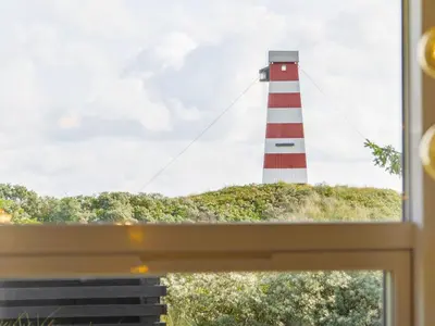 a red and white lighthouse seen through a window at Renovated Retreat with Pool - By Traum Ferienwohnungen in Thisted