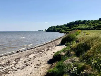 a sandy beach next to a body of water at 10 person holiday home in Roslev-By Traum in Roslev