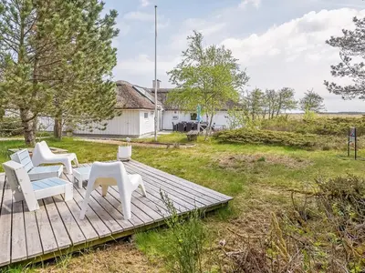 a wooden deck with two white chairs and a building at 10 person holiday home in Fjerritslev-By Traum in Fjerritslev