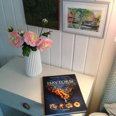 a table with a vase of flowers and a book at Glædegården -Glaede Landhof- 12 beds! in Frøstrup
