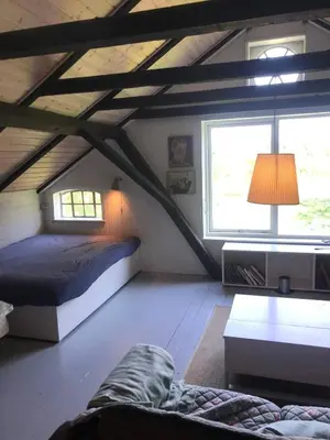 a bedroom with a bed and a window in a attic at Glædegården -Glaede Landhof- 12 beds! in Frøstrup