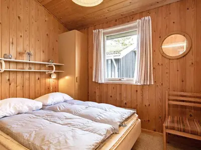 a bedroom with a bed in a wooden wall at Cozy Cottage near Blokhus - By Traum Ferienwohnungen in Blokhus