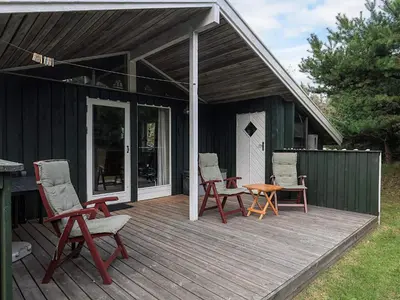 a house with chairs and a table on a deck at Cozy Cottage near Blokhus - By Traum Ferienwohnungen in Blokhus