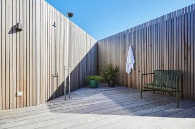 a green chair sitting on a deck next to a wooden fence at Vesterlandet in Vestervig