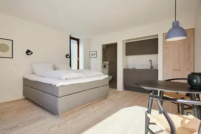a bedroom with a bed and a table and a kitchen at Vesterlandet in Vestervig
