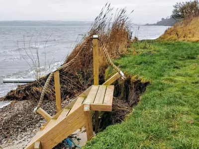 a wooden bench sitting on the side of a beach at 7 person holiday home in Lemvig-By Traum in Lemvig