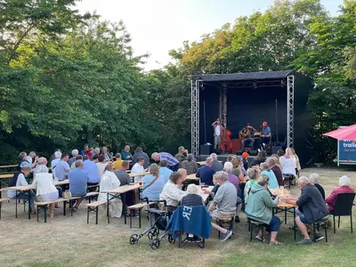 a crowd of people sitting at tables in front of a stage at Room 17 - Hawkraft kulturhotel in Vestervig