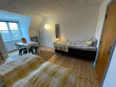 a bedroom with two beds and a table and a desk at Room 17 - Hawkraft kulturhotel in Vestervig
