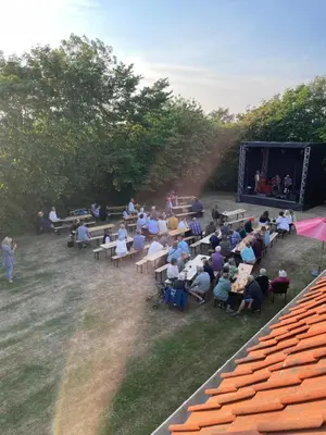 a crowd of people sitting at tables watching a stage at Room 15 - Hawkraft kulturhotel in Vestervig