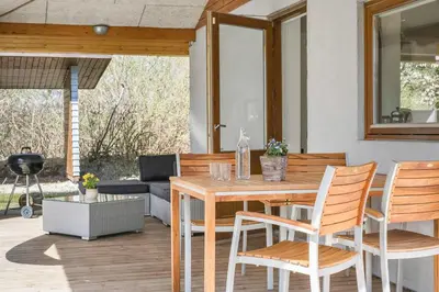 a wooden table and chairs on a patio at Wellness Oase med Sauna, Fodbad og Højhastighed Internet i Naturens Fred og Ro in Nibe