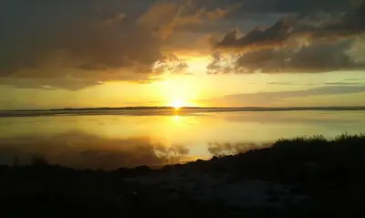a sunset over a body of water with the sun setting at Wellness Oase med Sauna, Fodbad og Højhastighed Internet i Naturens Fred og Ro in Nibe