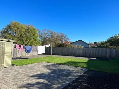 a yard with a fence and a clothesline withothes hanging on it at Hyggeligt byhus in Harboør