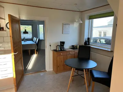 a small kitchen with a small table and a table at Hyggeligt byhus in Harboør
