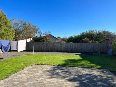 a backyard with a fence and aicked yard with a yard at Hyggeligt byhus in Harboør