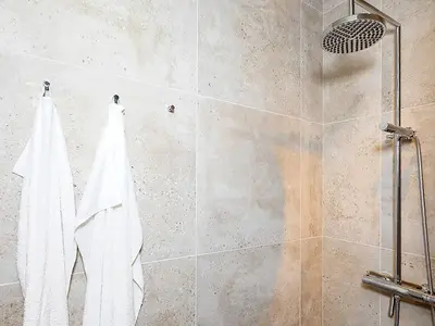 a shower with two white towels hanging on a wall at 6 person holiday home in Saltum-By Traum in Saltum