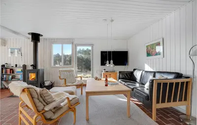 a living room with a couch and a table at 3 Bedroom Cozy Home In Blokhus in Blokhus