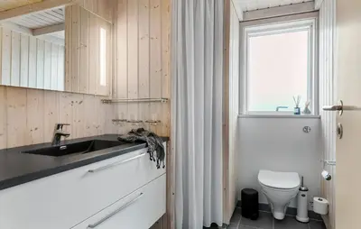 a bathroom with a sink and a toilet and a window at Awesome Home In Løkken With Kitchen in Løkken