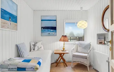 a bedroom with a bed and a chair and a table at Stunning Home In Blokhus in Blokhus