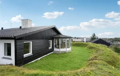 a black house on top of a grassy hill at Stunning Home In Blokhus in Blokhus
