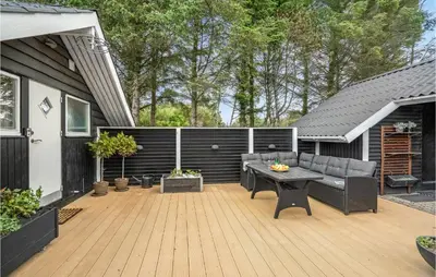 a patio with a couch and a table on a deck at Nice Home In Løkken With Kitchen in Løkken