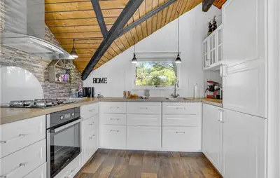 a kitchen with white cabinets and a wooden ceiling at Nice Home In Løkken With Kitchen in Løkken