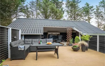 a patio with a couch and a table on a deck at Nice Home In Løkken With Kitchen in Løkken