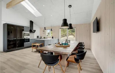 a kitchen and dining room with a wooden table and chairs at Nice Home In Løkken With Sauna in Løkken