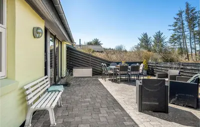 a patio with a table and chairs on a house at Gorgeous Home In Blokhus With Sauna in Blokhus