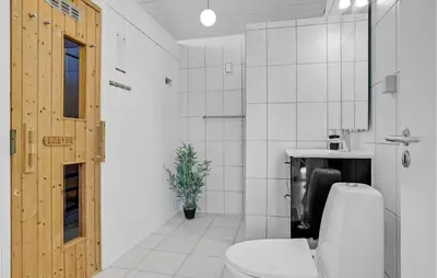a white bathroom with a toilet and a sink at Gorgeous Home In Blokhus With Sauna in Blokhus
