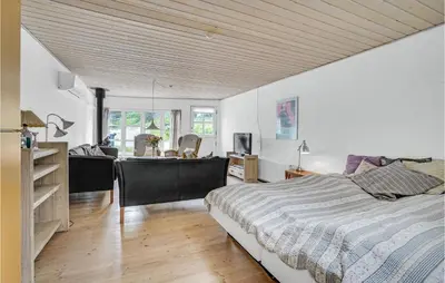 a bedroom with a large bed and a dining room at Gorgeous Apartment In Blokhus With Wifi in Blokhus