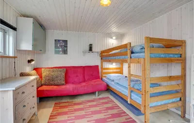 a bedroom with a bunk bed and a red couch at 3 Bedroom Pet Friendly Home In Blokhus in Blokhus