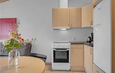 a kitchen with a table and a stove and cabinets at Cozy Home In Pandrup With Wifi in Pandrup