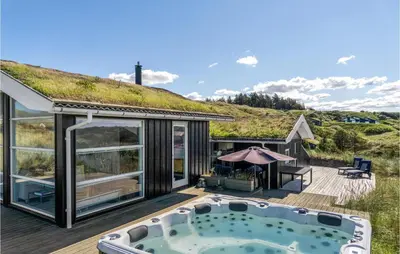 a house with a hot tub on a deck at 5 Bedroom Stunning Home In Blokhus in Blokhus
