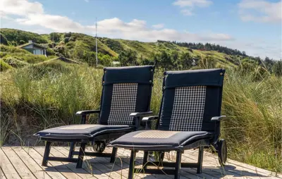 two chairs sitting on top of a wooden deck at 5 Bedroom Stunning Home In Blokhus in Blokhus