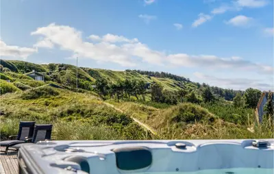 a boat on a dock with chairs and a hill at 5 Bedroom Stunning Home In Blokhus in Blokhus