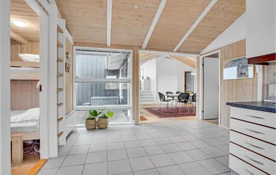 an open kitchen and living room with wooden ceilings at 5 Bedroom Stunning Home In Blokhus in Blokhus