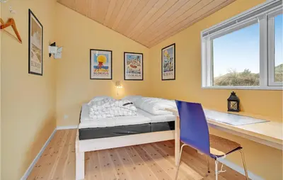 a bedroom with a bed and a desk and a window at 5 Bedroom Stunning Home In Blokhus in Blokhus