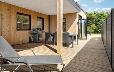 a deck with chairs and a stove on a house at Stunning Home In Blokhus With Kitchen in Blokhus
