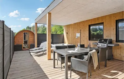 a patio with a table and chairs on a deck at Stunning Home In Blokhus With Kitchen in Blokhus