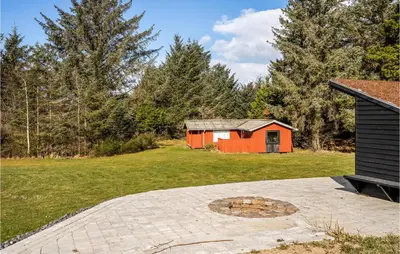 a small red building in a field with a house at 2 Bedroom Cozy Apartment In Blokhus in Blokhus
