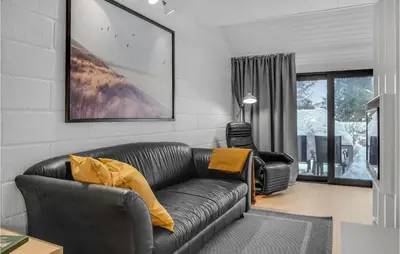 a living room with a black leather couch at 2 Bedroom Cozy Apartment In Blokhus in Blokhus