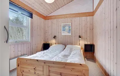 a bedroom with a large bed in a wooden wall at 3 Bedroom Gorgeous Home In Pandrup in Pandrup