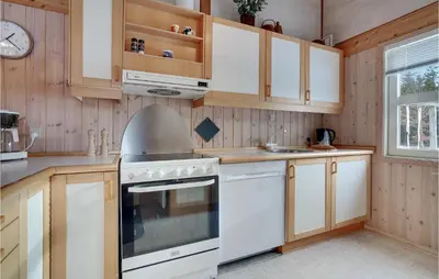 a kitchen with white appliances and wooden cabinets at 3 Bedroom Gorgeous Home In Pandrup in Pandrup