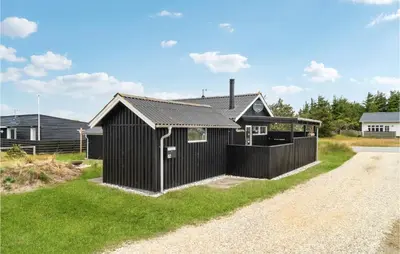 a black house on the side of a gravel road at Nice Home In Thisted With Kitchen in Thisted