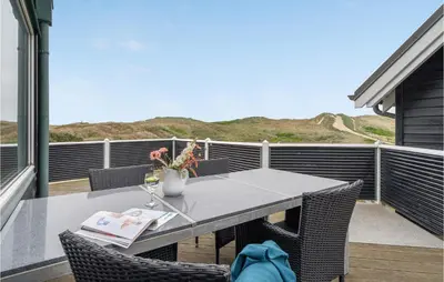 a table and chairs on the balcony of a house at Lovely Home In Harboøre With Sauna in Harboør