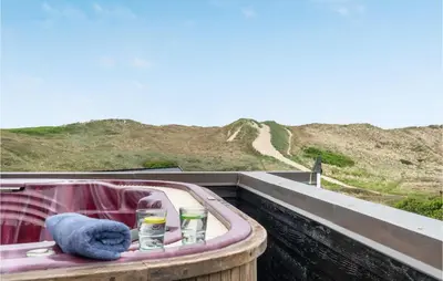 a bath tub with a towel and two glasses and a blue towel at Lovely Home In Harboøre With Sauna in Harboør