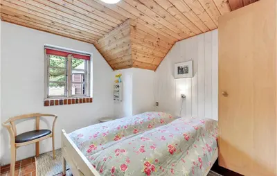 a bedroom with a bed and a chair in it at Cozy Home In Vestervig With Sauna in Vestervig