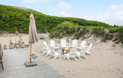 a table with chairs and an umbrella on the beach at Gorgeous Home In Lemvig With Sauna in Lemvig
