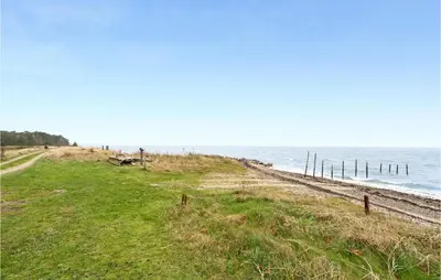 a grassy hill next to a beach with the ocean at Beautiful Home In Thyholm With Wifi in Thyholm