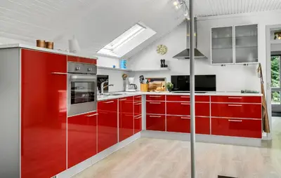 a red kitchen with stainless steel appliances and red cabinets at 3 Bedroom Awesome Home In Thyholm in Thyholm